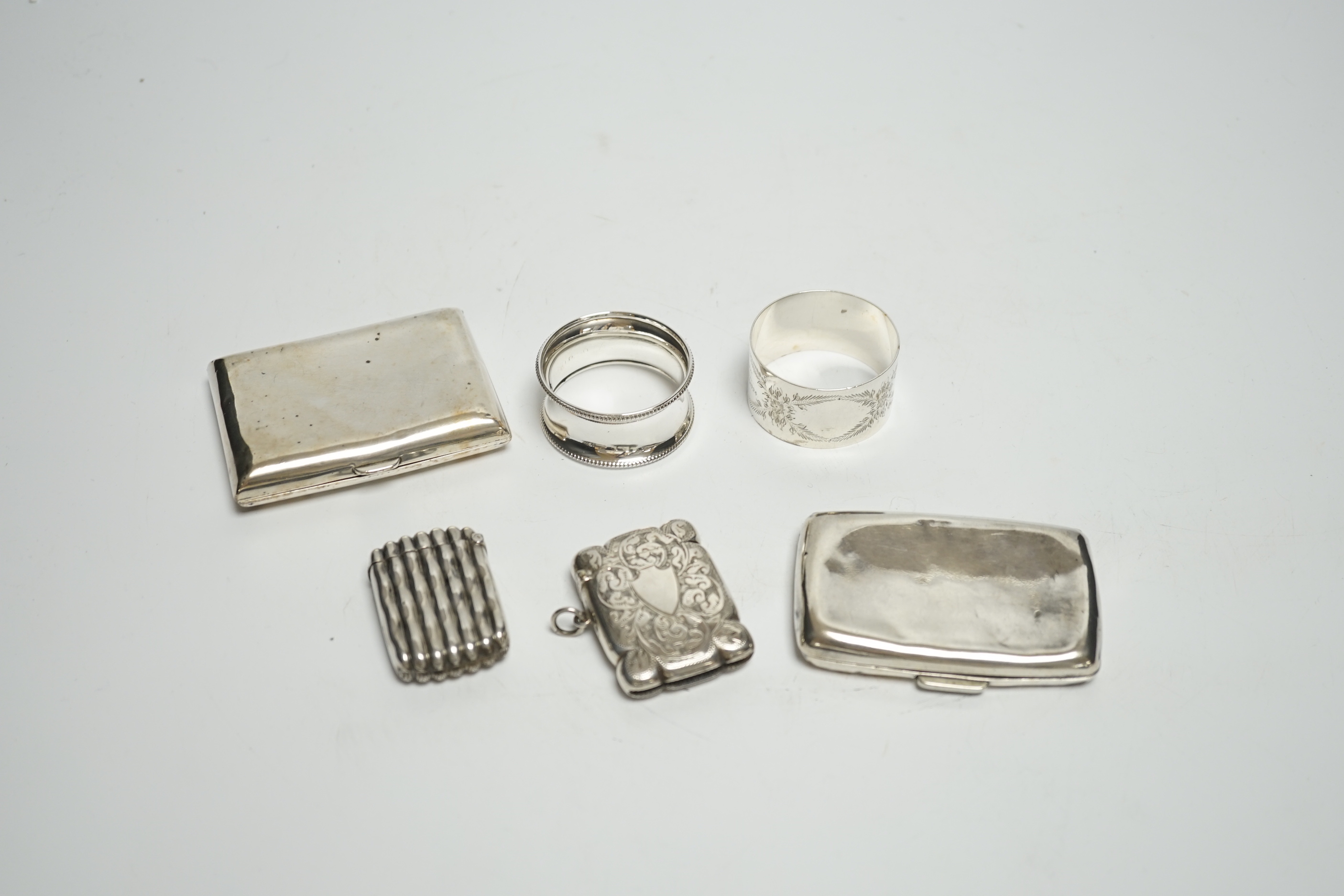 Two silver napkin rings, two silver cigarette cases and two silver vesta cases.